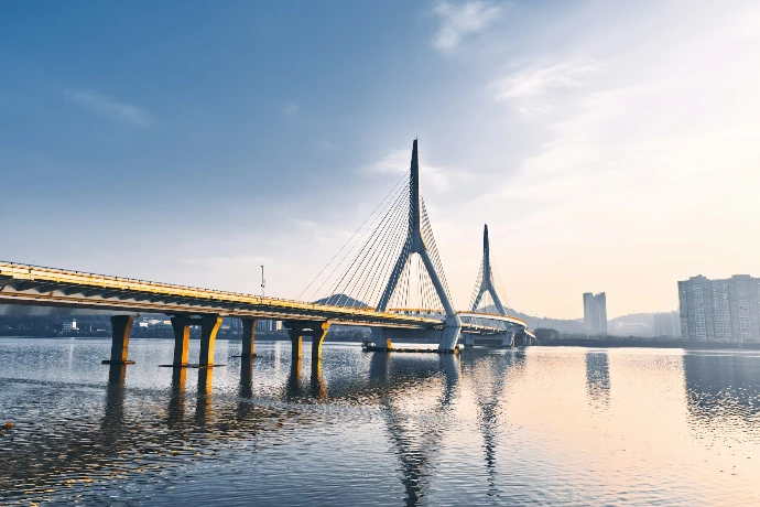 Modern cable-stayed bridge over calm water at sunrise